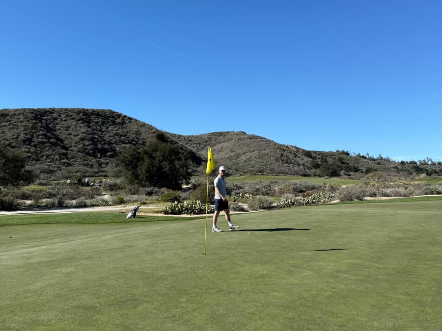 Golfer teeing off with mountains behind